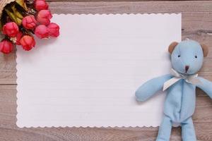 tabla de tablones de madera papel de carta blanco muñeca de oso azul flor rosa foto