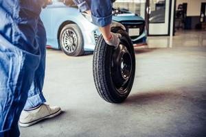 Mecánica de automóviles cambiando el neumático en el garaje del taller de reparación de automóviles