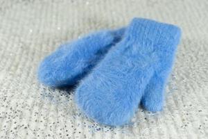 Blue wool mittens on a bright shiny background
