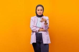 Unhappy Asian business woman pointing at camera over yellow background photo