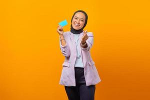 Portrait of cheerful beautiful Asian woman holding credit card photo