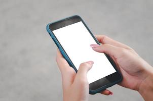 mano de mujer usando un teléfono móvil simulando una pantalla en blanco. foto