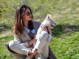 Young woman posing for a photo with her white schnauzer puppy.