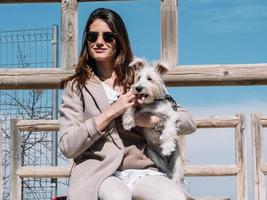 Woman with Schnauzer dog poses sitting on railing photo