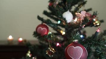 Christmas tree and heart shaped balls with candles at home interior video