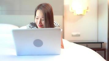 jovem asiática usando um laptop na cama