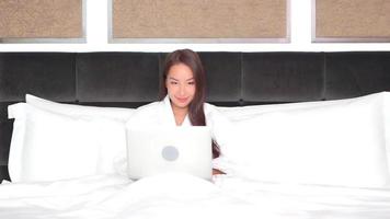 Young asian woman uses a laptop in bed video