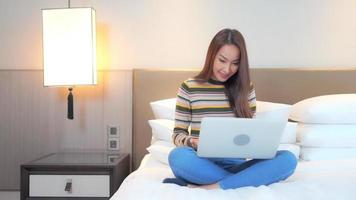 Young asian woman uses a laptop in bed video