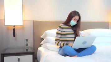 Young asian woman uses a laptop in bed video