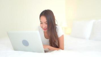 Young asian woman uses a laptop in bed video