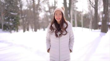 Joven mujer asiática disfruta de una sonrisa alrededor de la nieve y el invierno video