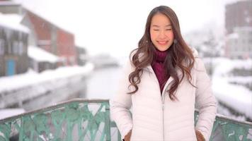 la giovane donna asiatica gode del sorriso intorno alla neve e all'inverno? video