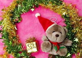 Teddy with christmas hat and decoration on pink backgrounds above photo