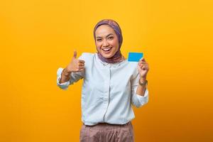 Beautiful Asian woman holding blank card and showing thumbs up