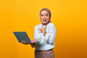 Beautiful Asian woman holding laptop with surprised expression