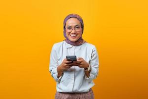 Sonriente mujer asiática con teléfono móvil y mirando a la cámara foto