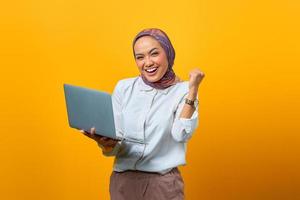 Portrait of excited Asian woman holding laptop photo