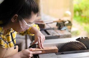 La mujer es artesanía trabajando madera cortada con sierras circulares herramientas eléctricas foto