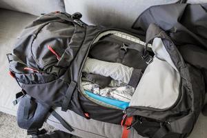 Empaque mochila de viaje negro rojo empacado, ropa y utensilios de viaje. foto