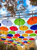 Autumn-themed umbrellas hang over the park alley photo