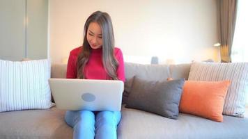 Young asian woman uses a laptop on the couch video