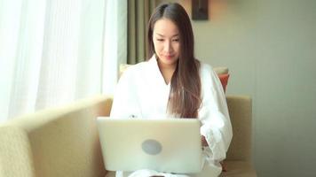 Young asian woman uses a laptop on the couch video