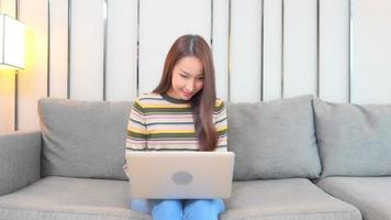 jonge Aziatische vrouw gebruikt een laptop op de bank
