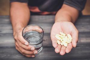 Bottle pouring pills with glass of water in a male's hand photo