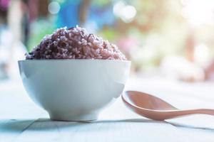 Cooked rice in bowl with spoon on wooden table photo