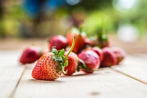 Ripe strawberries on wooden table with blurred nature background