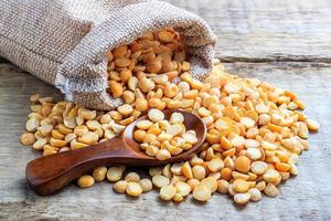 Dried peas in a bag with a wooden spoon on a wooden background photo