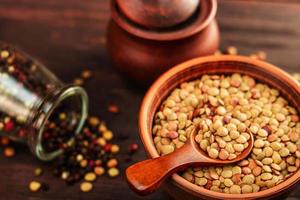 Lentils in a clay vessel, with a wooden spoon and a jar of spices photo