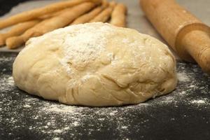 Bread sticks on paper and a piece of dough with a rolling pin photo