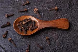 Clove in a wooden spoon against a dark concrete photo