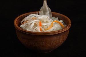 Sauerkraut and fork in a clay Cup on a concrete background photo