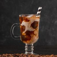 Cold coffee with ice and cream in a glass with straw photo