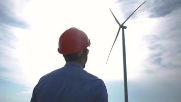 Male worker in helmet watching on the wind turbine video