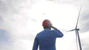 Male worker in helmet watching on the wind turbine video