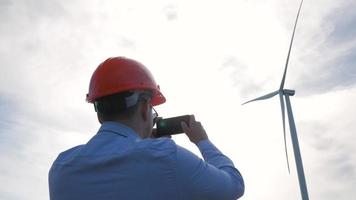 Trabajador en casco mirando en la turbina eólica video