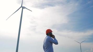 Trabajador en casco mirando en la turbina eólica video