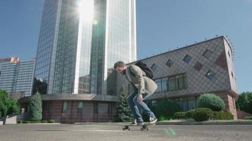 Junger bärtiger männlicher Geschäftsmann fährt auf Skateboard im Freien