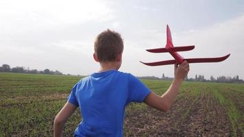 Male boy play with toy airplane in summer fields video