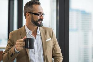 Young handsome business bearded man drinking cup of coffee photo