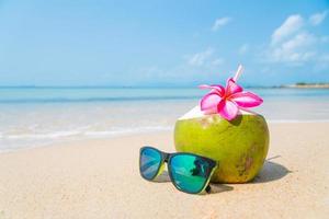 Coconut and sunglasses on tropical beach.