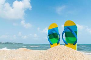sandalias de playa en la costa arenosa. concepto de verano foto