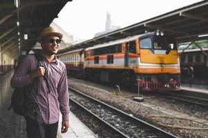 hombre joven viajero en la plataforma de la estación de tren. concepto de viaje.