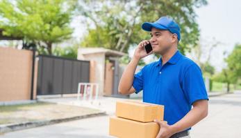 Blue Delivery man holding parcel cardboard box and talking on phone. photo