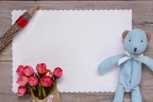 Wooden table white letter paper blue bear doll pencil rose flower photo