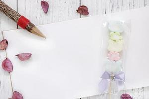 Paper with candy, pencil and petals photo