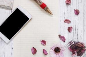 Pencil, phone and petals on paper photo